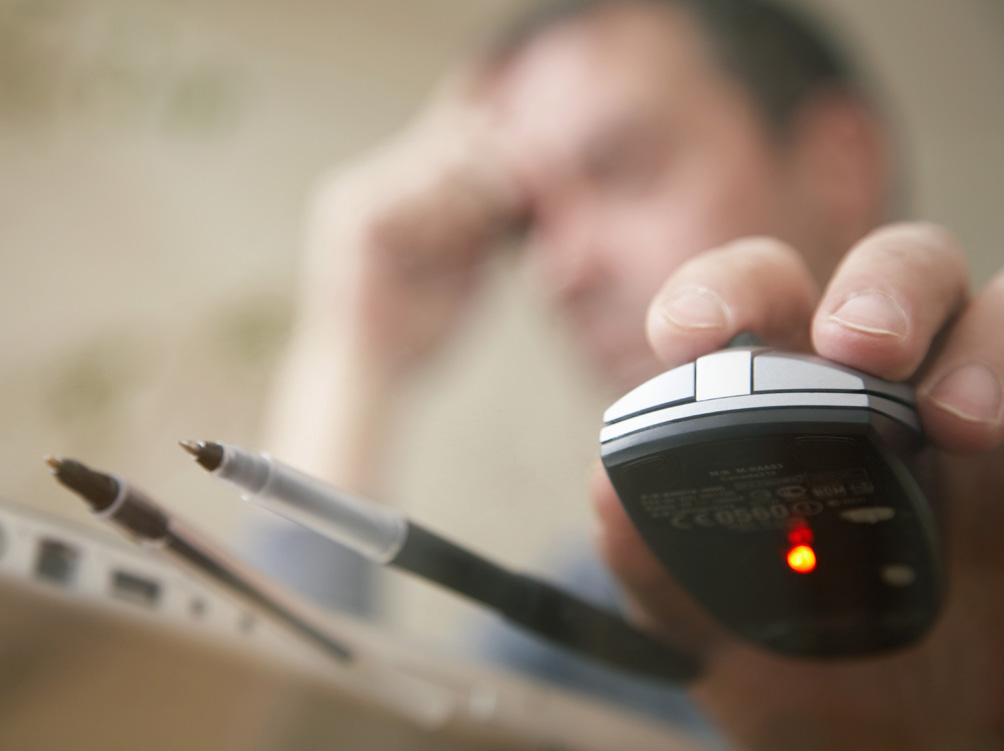 Man sitting at desk using computer mouse, view through glass desktop